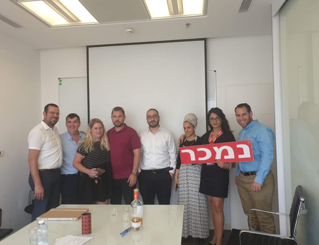 צוות ולקוחות עם שלט נמכר
